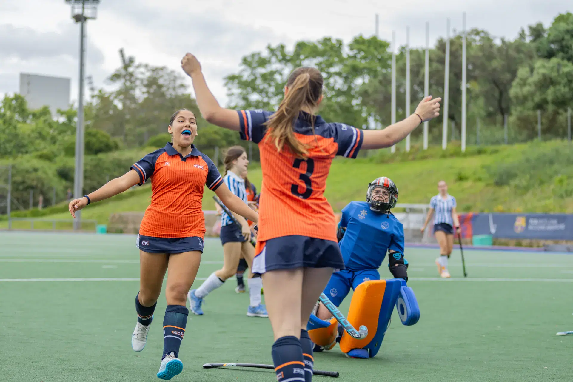 Catalonia HC players in orange celebrating a goal on the hockey pitch